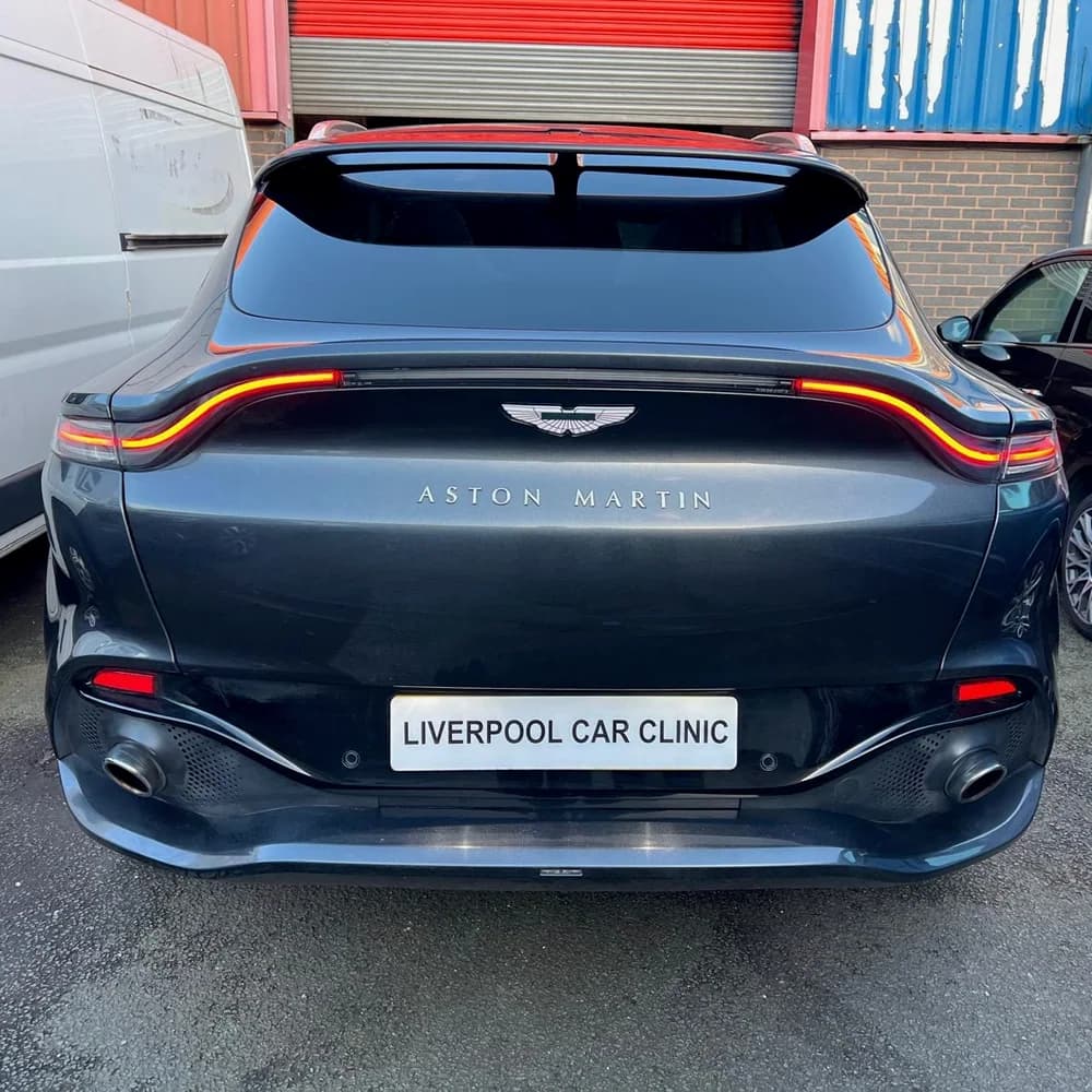 The rear of a dark grey Aston Martin DBX carrying a Liverpool Car Clinic trade plate.