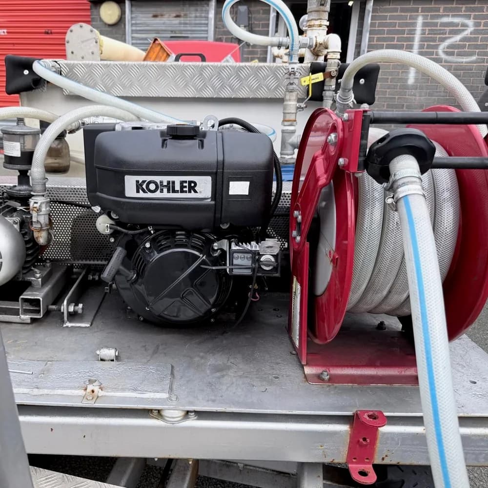 A Kohler engine, pump and red hose reel on a piece of specialist utility equipment.