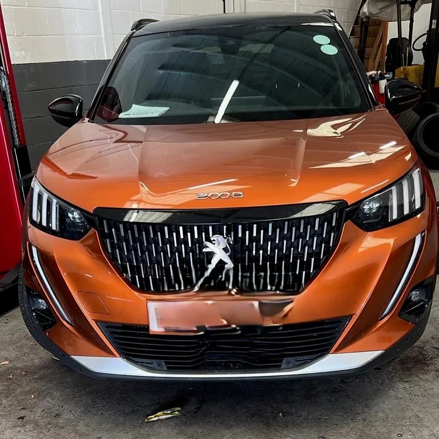 The front of an orange Peugeot 2008 in the workshop.