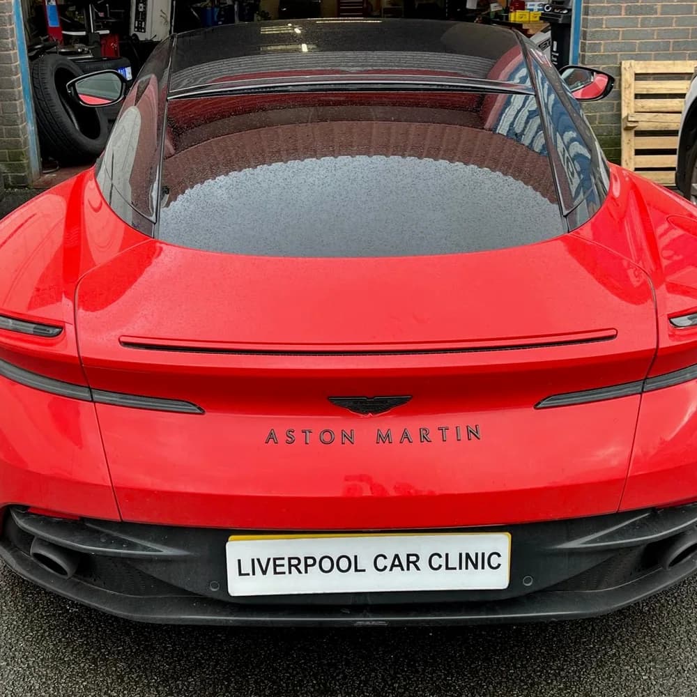 The rear of a red Aston Martin carrying a Liverpool Car Clinic trade plate.