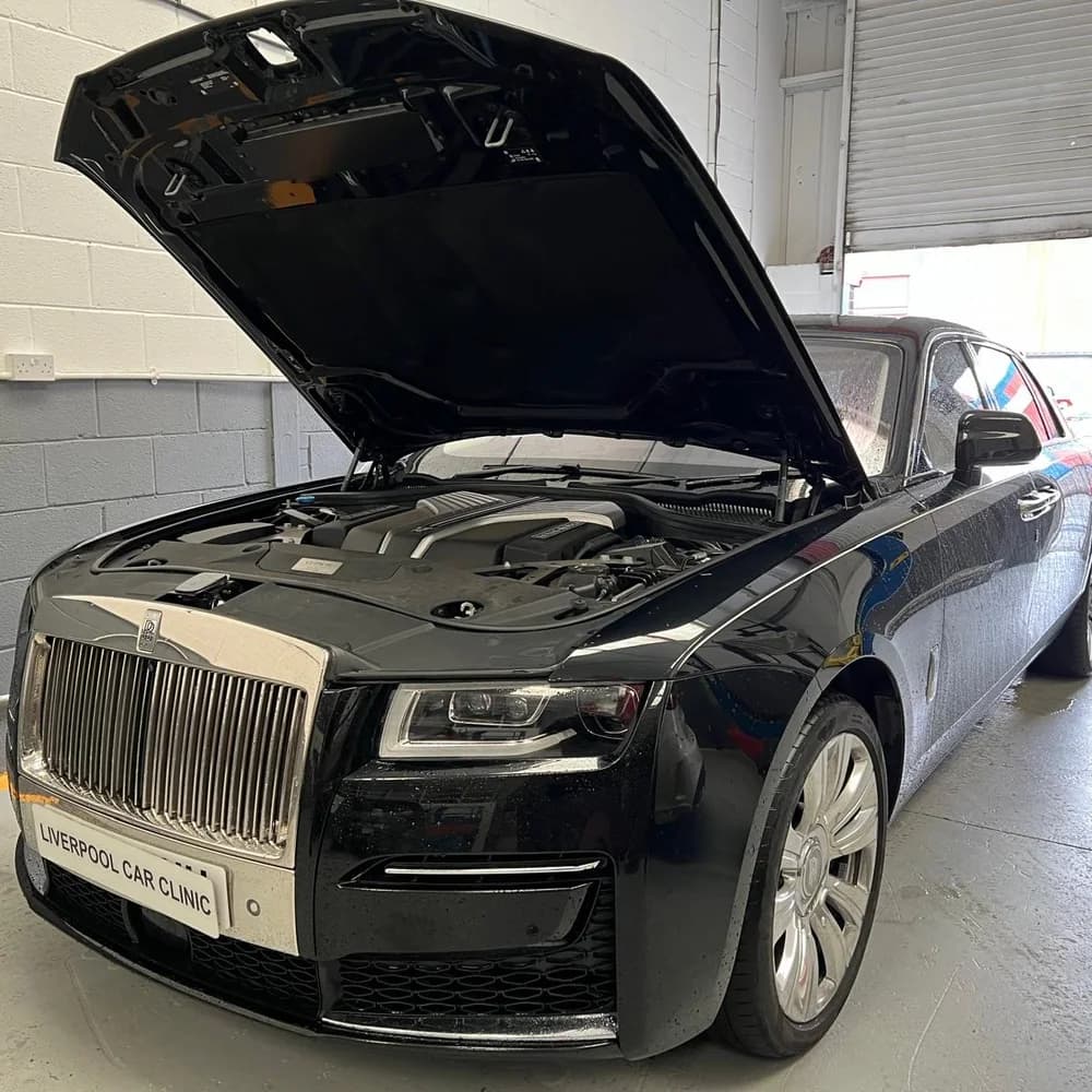 A black Rolls-Royce in the workshop with the bonnet up, carrying a Liverpool Car Clinic trade plate.