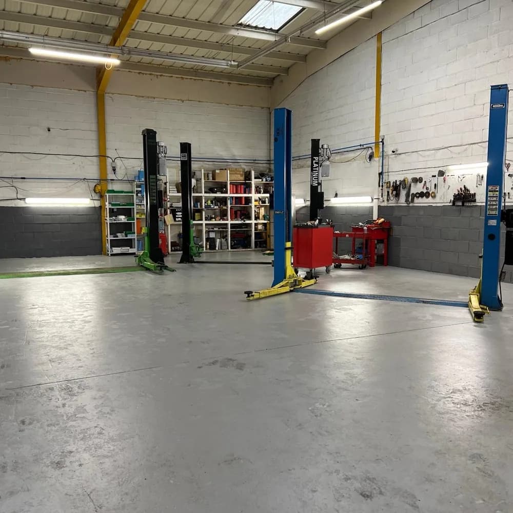 The empty workshop, with two-post lifts, a tool wall and parts shelving.