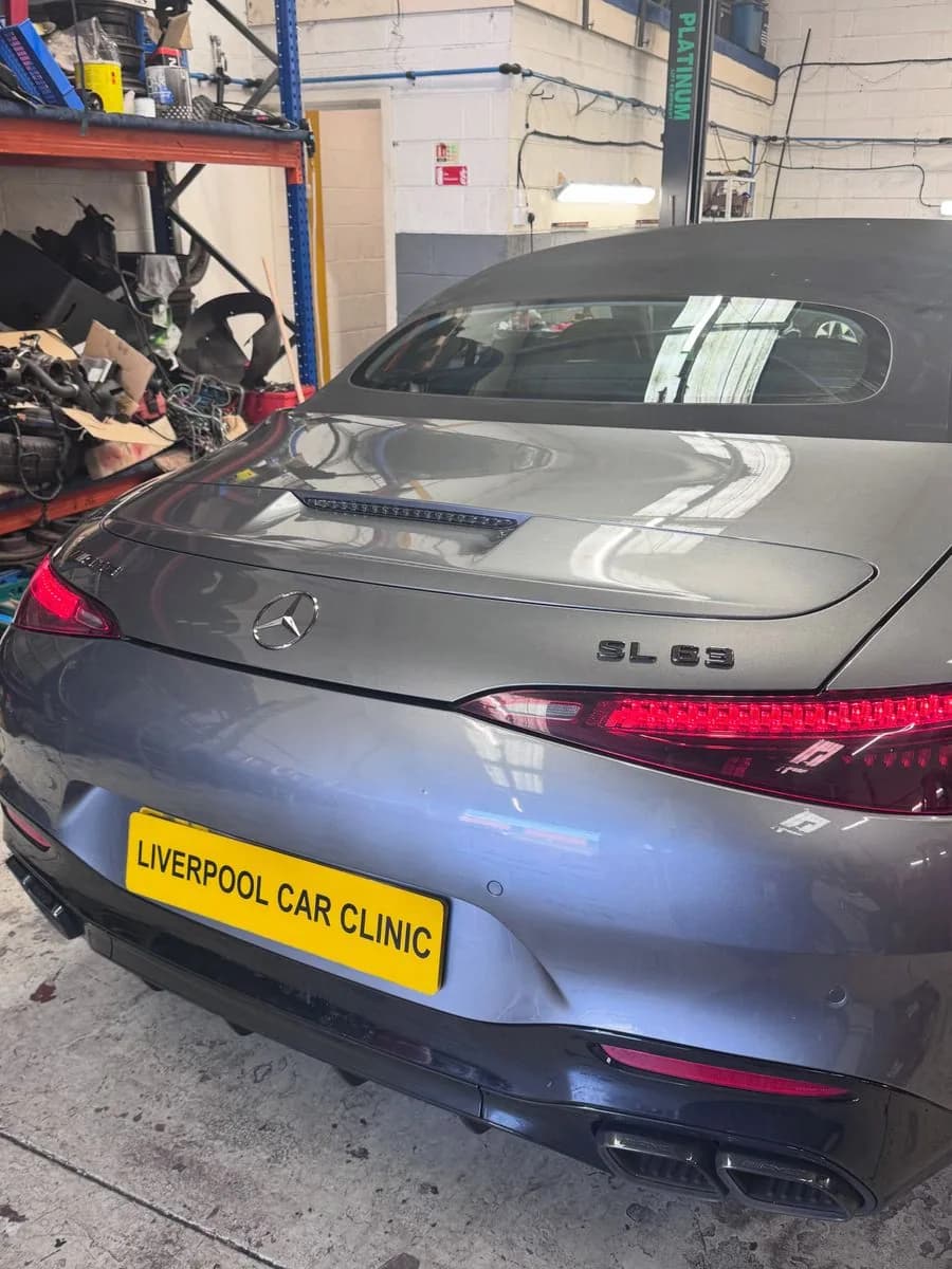 A Mercedes-AMG SL 63 parked in a workshop bay alongside parts shelving.