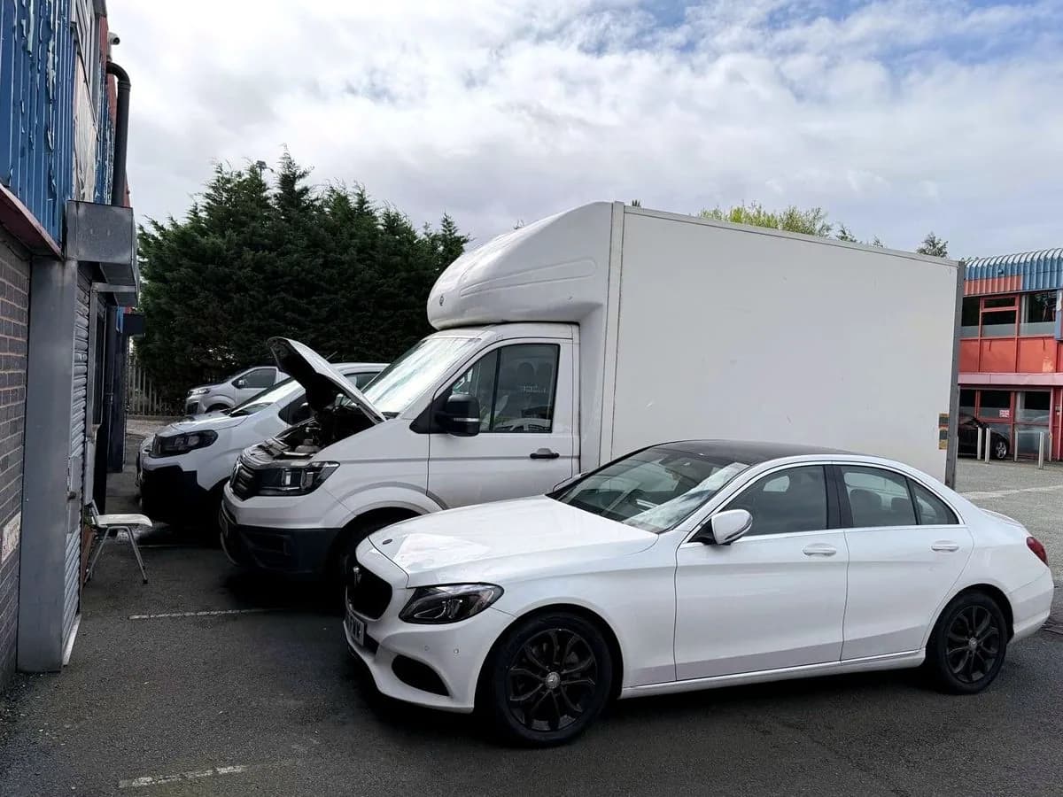A Luton van, a saloon car and light commercial vehicles parked outside the unit awaiting work.