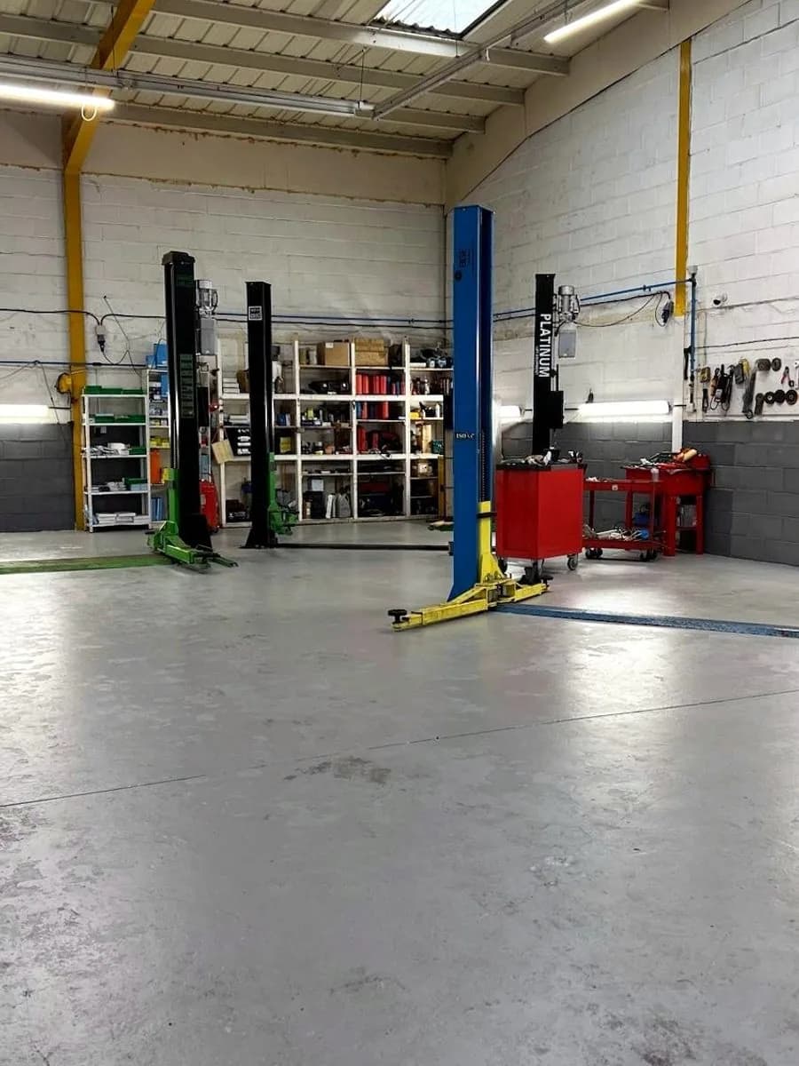 The Liverpool Car Clinic workshop floor showing two-post ramps, tool trolleys and parts shelving.